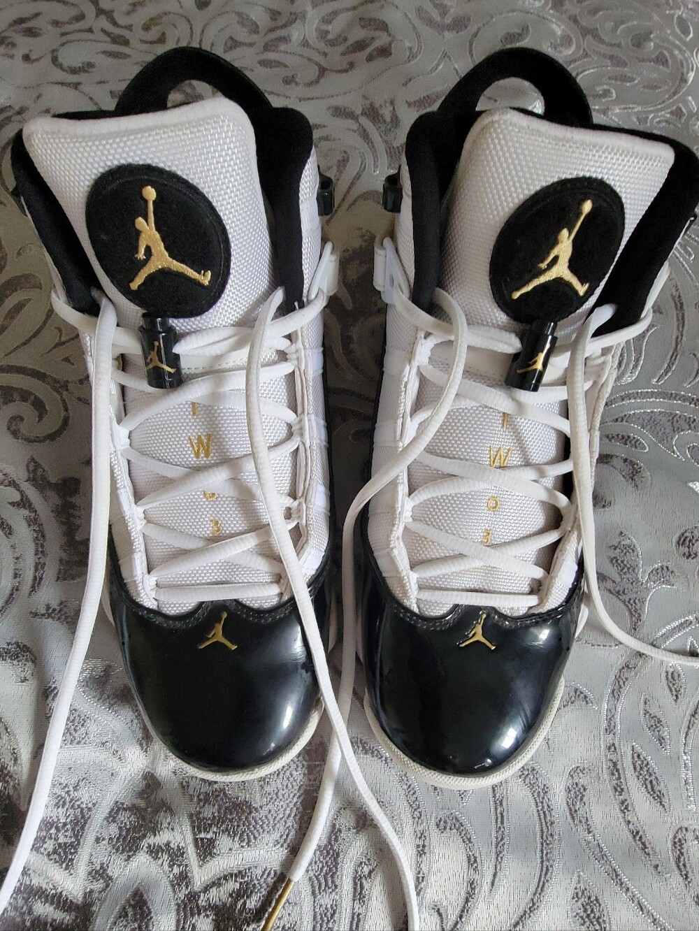 These are Nike Air Jordan 6 Rings basketball shoes in the white, black, And Meta